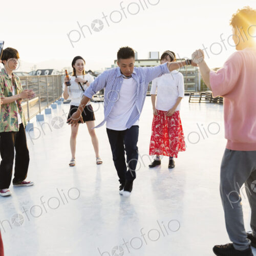 Group of young Japanese men and women dancing on a rooftop in an urban setting. Group of young Japanese men and women dancing on a rooftop in an urban setting.