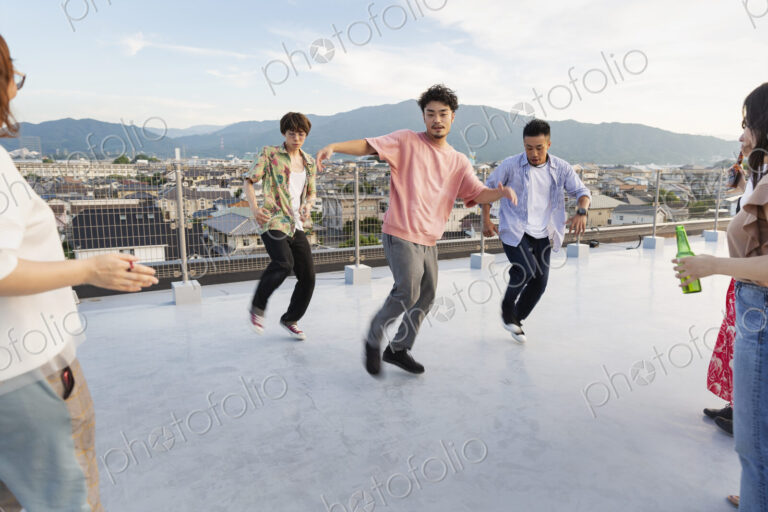 Group of young Japanese men and women dancing on a rooftop in an urban setting.