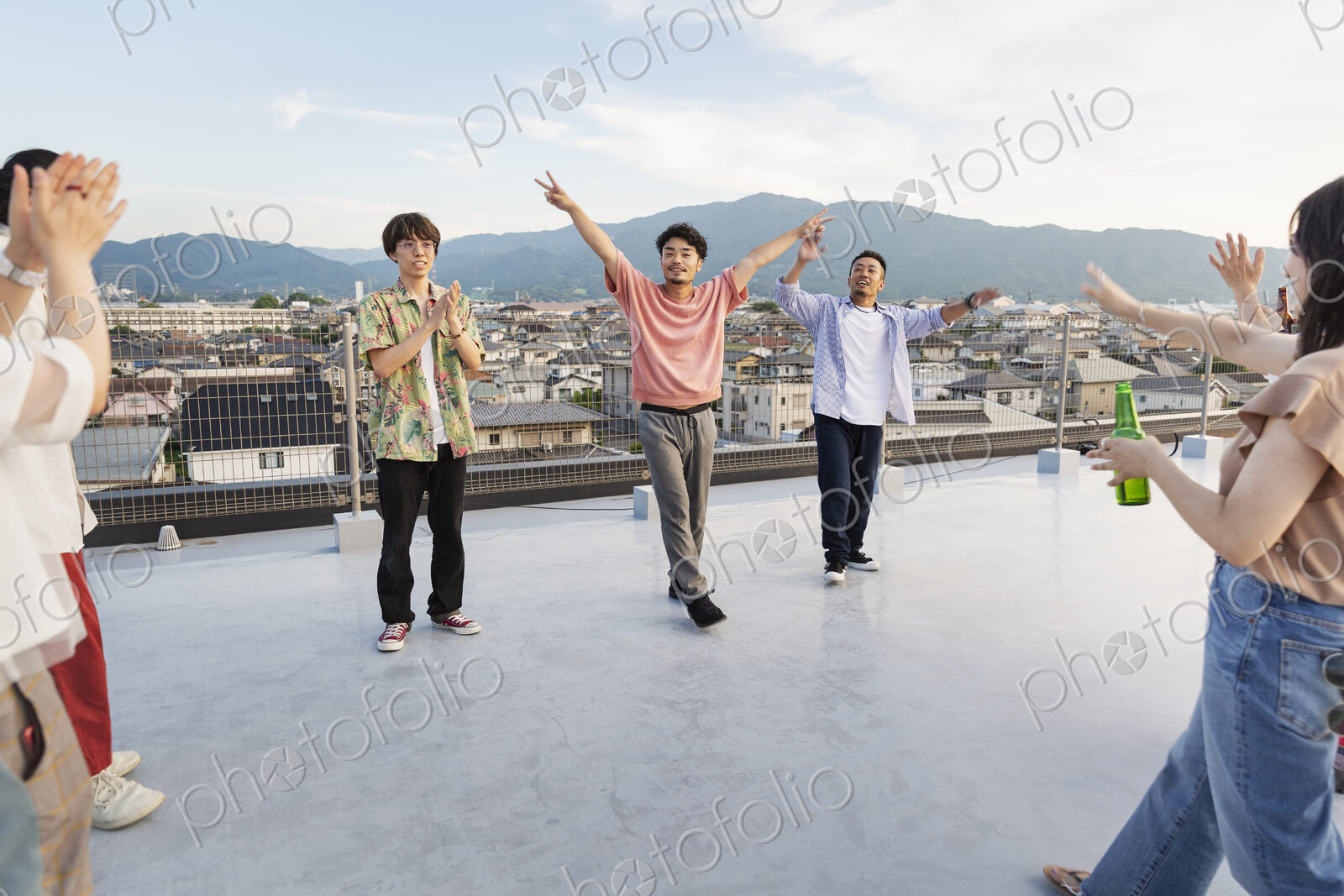 Group of young Japanese men and women dancing on a rooftop in an urban setting.