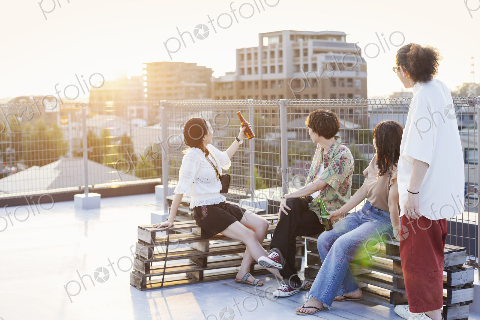 Group of young Japanese men and women sitting on a rooftop in an urban setting.