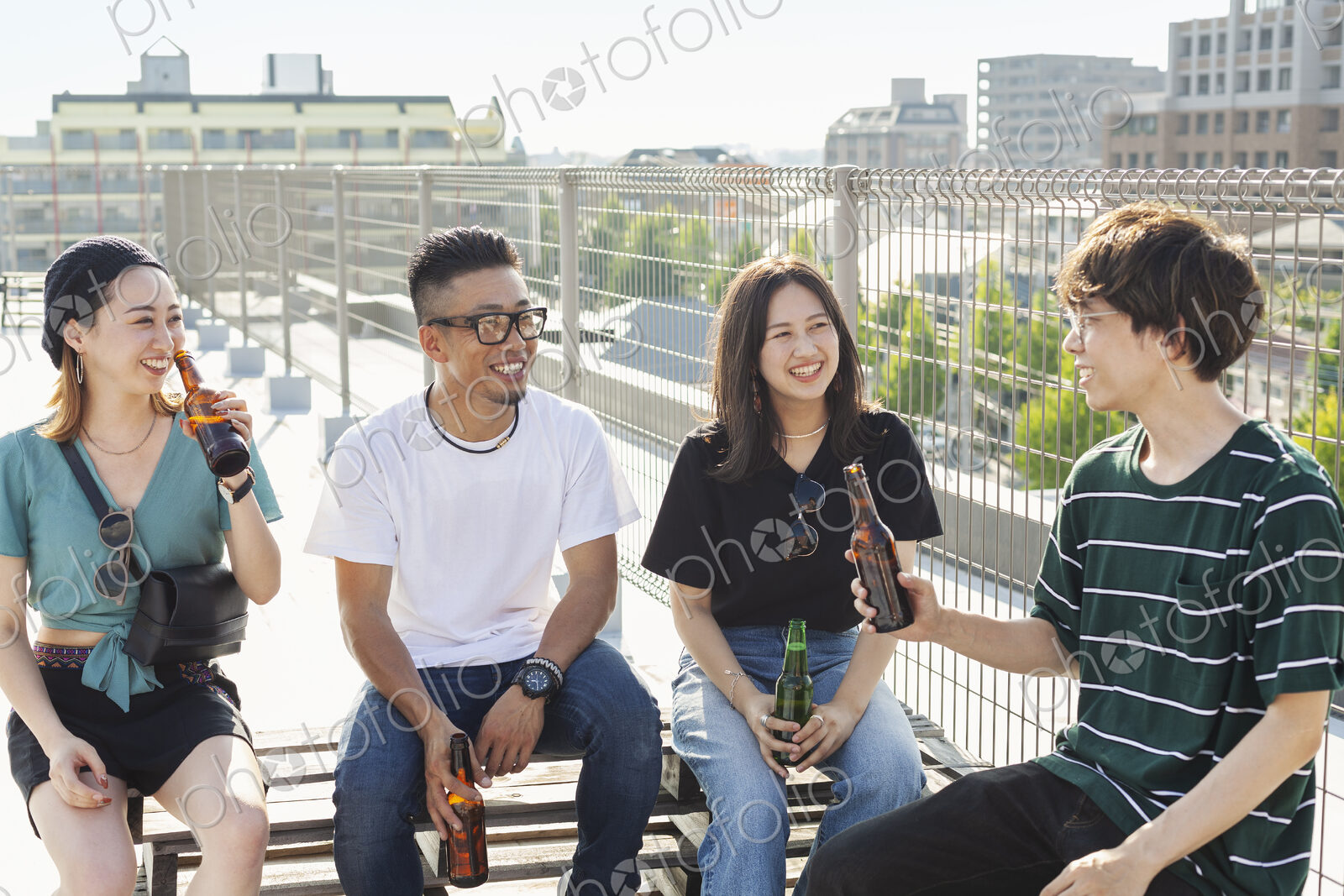 Group of young Japanese men and women sitting on a rooftop in an urban setting,…