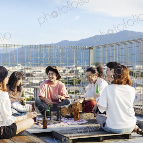 Group of young Japanese men and women sitting on a rooftop in an urban setting,… Group of young Japanese men and women sitting on a rooftop in an urban setting,…