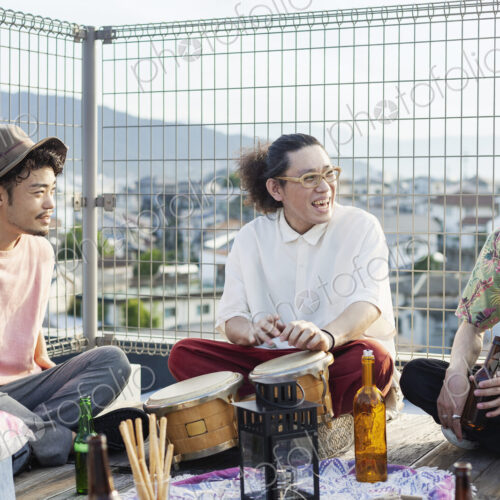 Group of young Japanese men and women sitting on a rooftop in an urban setting,… Group of young Japanese men and women sitting on a rooftop in an urban setting,…