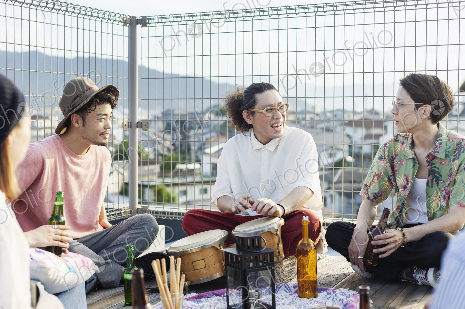 Group of young Japanese men and women sitting on a rooftop in an urban setting,…