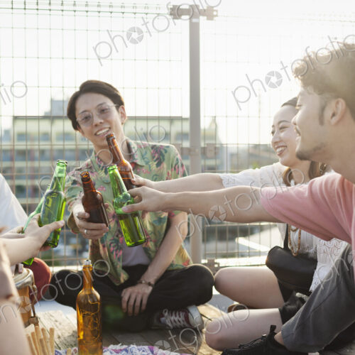Group of young Japanese men and women sitting on a rooftop in an urban setting,… Group of young Japanese men and women sitting on a rooftop in an urban setting,…