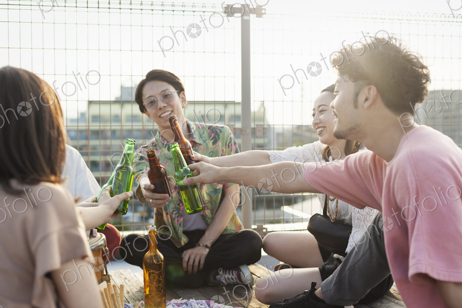 Group of young Japanese men and women sitting on a rooftop in an urban setting,…