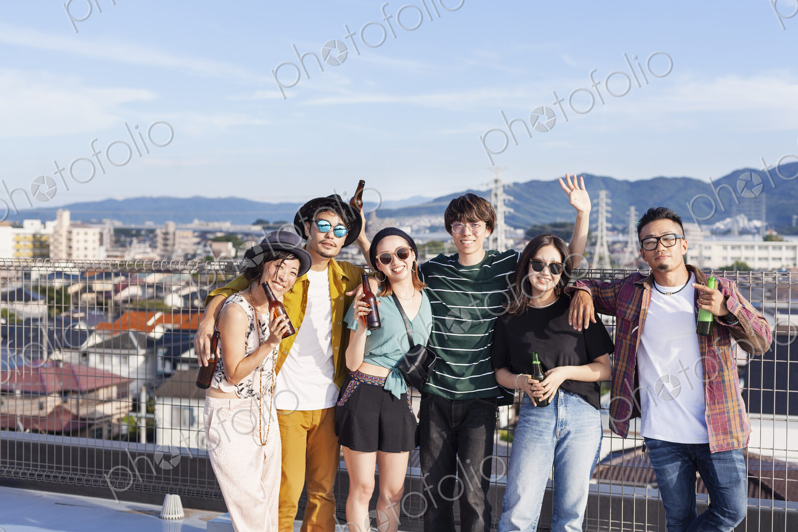 Group of young Japanese men and women standing on a rooftop in an urban setting.