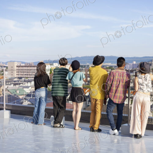 Group of young Japanese men and women standing on a rooftop in an urban setting. Group of young Japanese men and women standing on a rooftop in an urban setting.