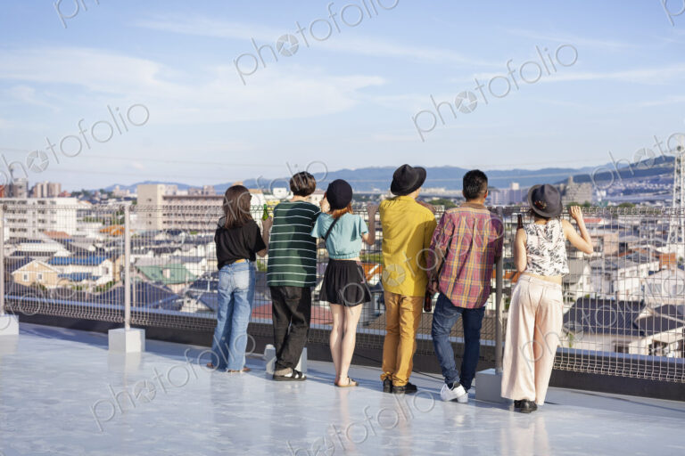 Group of young Japanese men and women standing on a rooftop in an urban setting.
