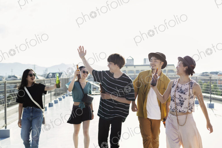 Group of young Japanese men and women standing on a rooftop in an urban setting.