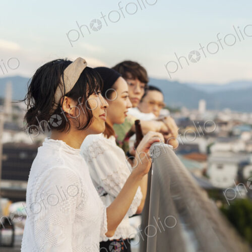 Group of young Japanese men and women standing on a rooftop in an urban setting.