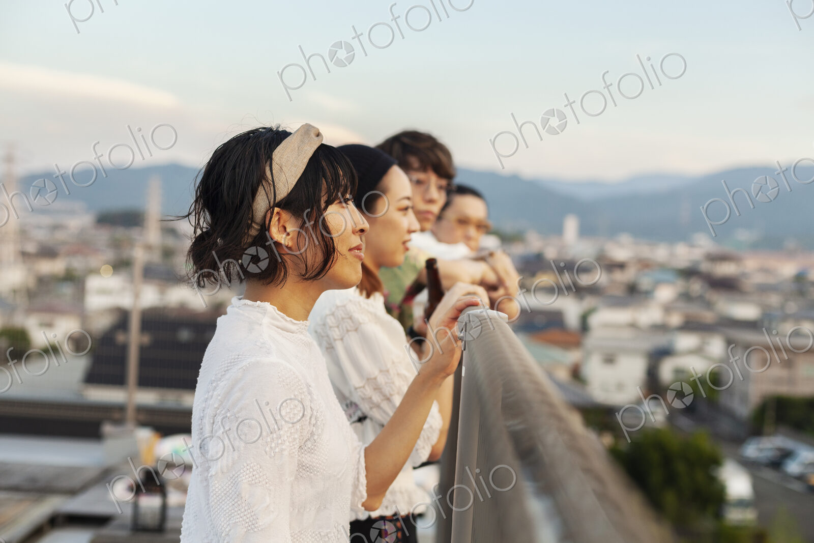 Group of young Japanese men and women standing on a rooftop in an urban setting.