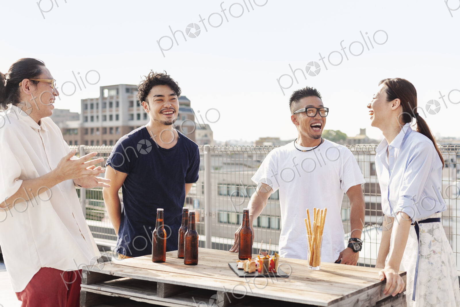 Group of young Japanese men and women standing on a rooftop in an urban setting,…