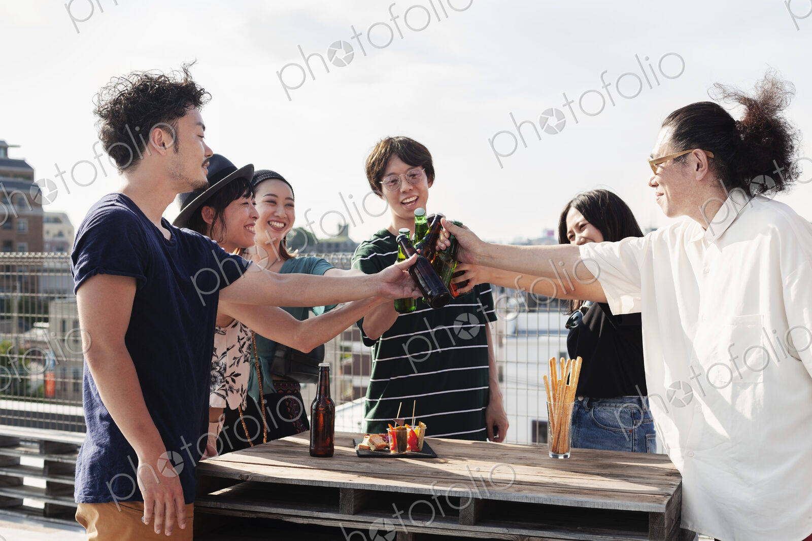 Group of young Japanese men and women standing on a rooftop in an urban setting,…
