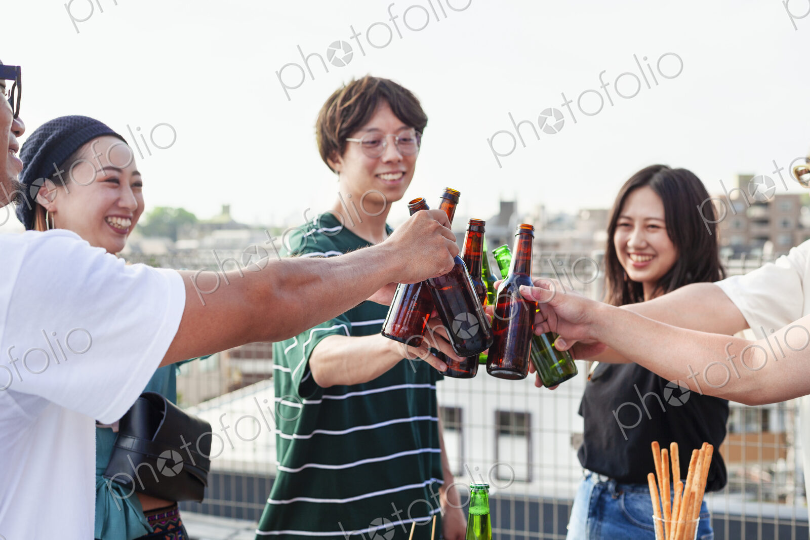 Group of young Japanese men and women standing on a rooftop in an urban setting,…