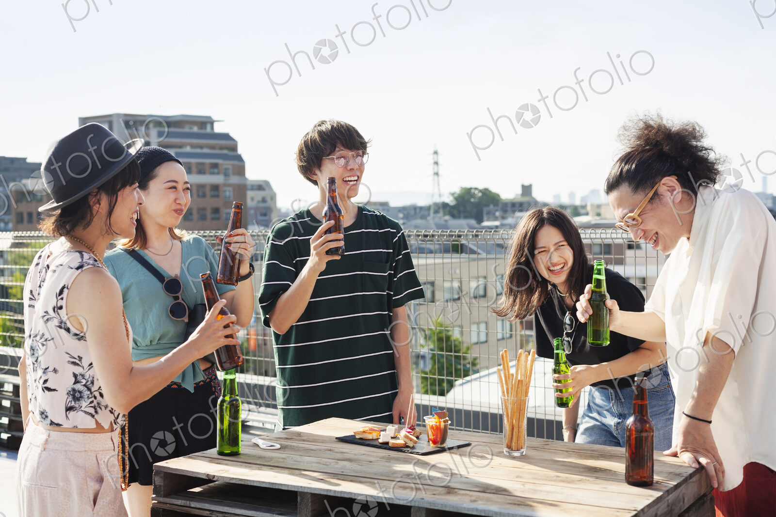 Group of young Japanese men and women standing on a rooftop in an urban setting,…