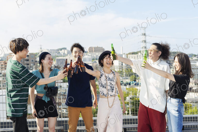 Group of young Japanese men and women standing on a rooftop in an urban setting,…