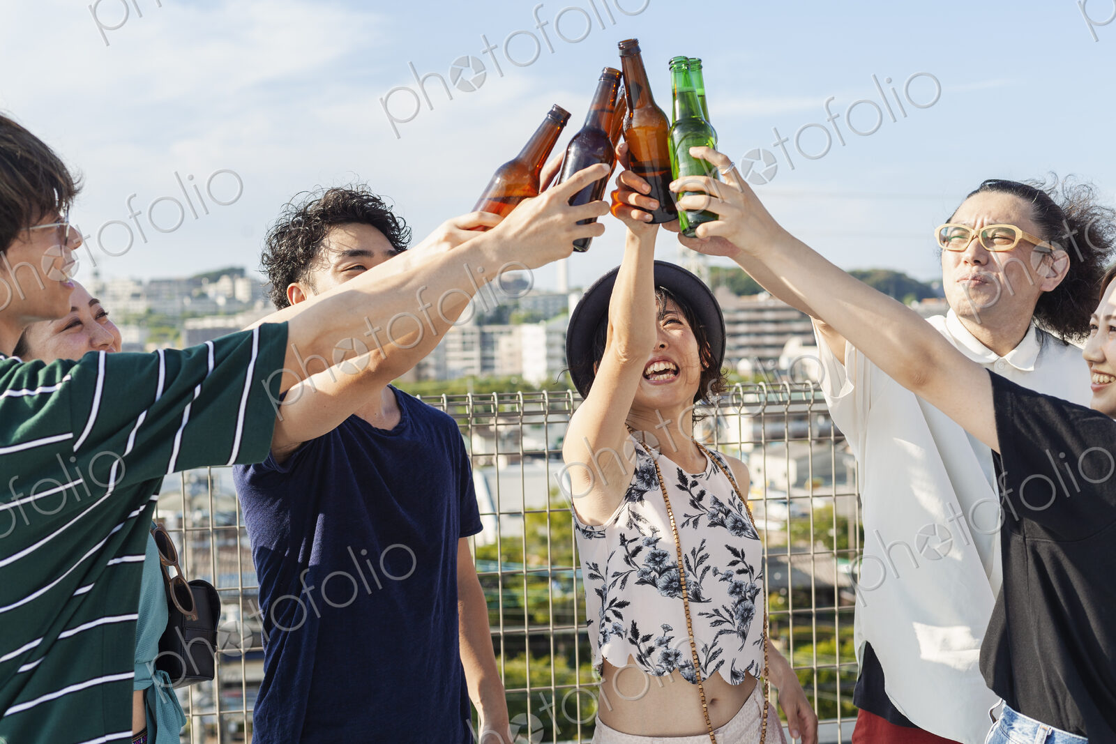 Group of young Japanese men and women standing on a rooftop in an urban setting,…