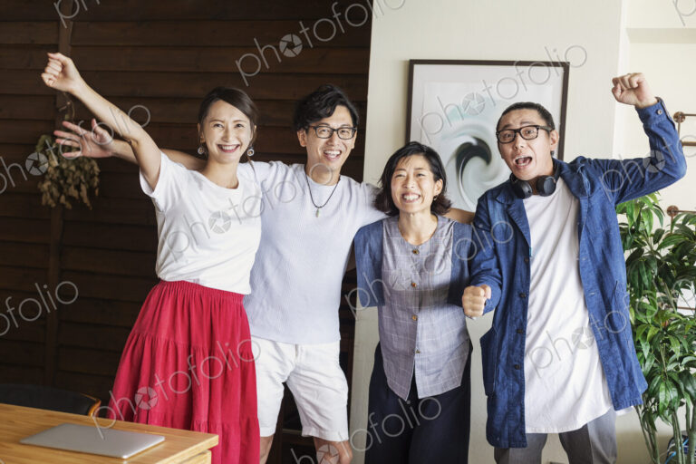 Group of young Japanese professionals in a co-working space, smiling and cheering at…