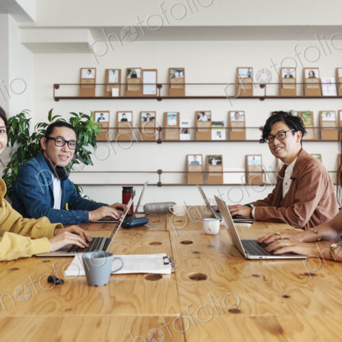 Group of young Japanese professionals working on laptop computers in a co-working space. Group of young Japanese professionals working on laptop computers in a co-working space.