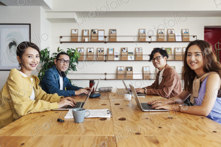 Group of young Japanese professionals working on laptop computers in a co-working space.