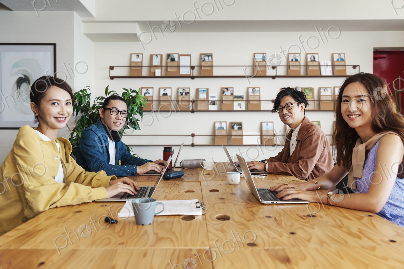 Group of young Japanese professionals working on laptop computers in a co-working space.
