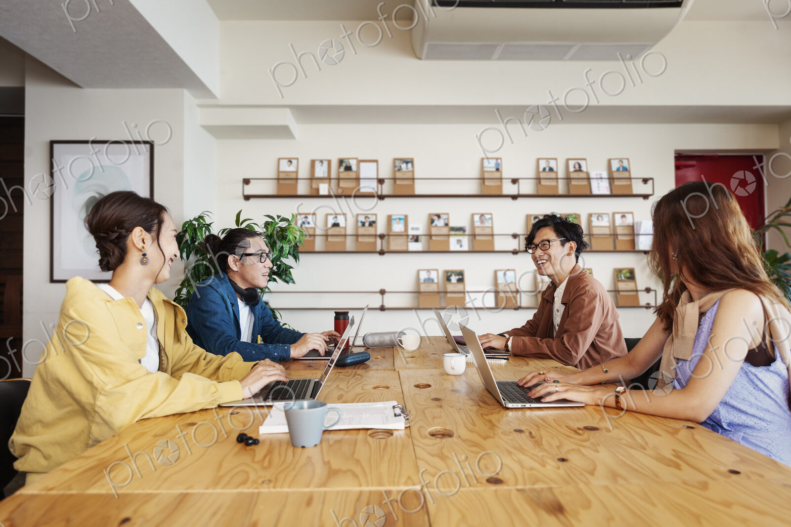 Group of young Japanese professionals working on laptop computers in a co-working space.