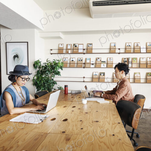 Group of young Japanese professionals working on laptop computers in a co-working space. Group of young Japanese professionals working on laptop computers in a co-working space.