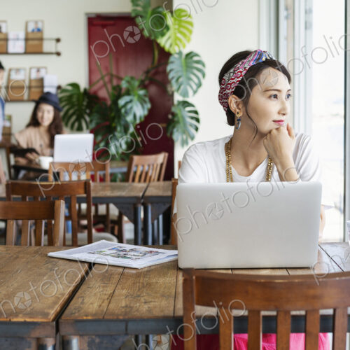 Group of young Japanese professionals working on laptop computers in a co-working space.