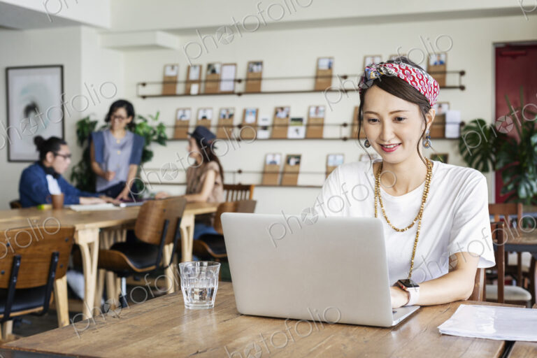 Group of young Japanese professionals working on laptop computers in a co-working space.