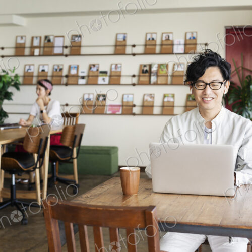Group of young Japanese professionals working on laptop computers in a co-working space. Group of young Japanese professionals working on laptop computers in a co-working space.