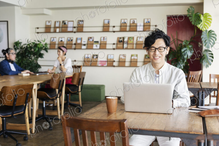 Group of young Japanese professionals working on laptop computers in a co-working space.