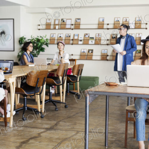 Group of young Japanese professionals working on laptop computers in a co-working space. Group of young Japanese professionals working on laptop computers in a co-working space.
