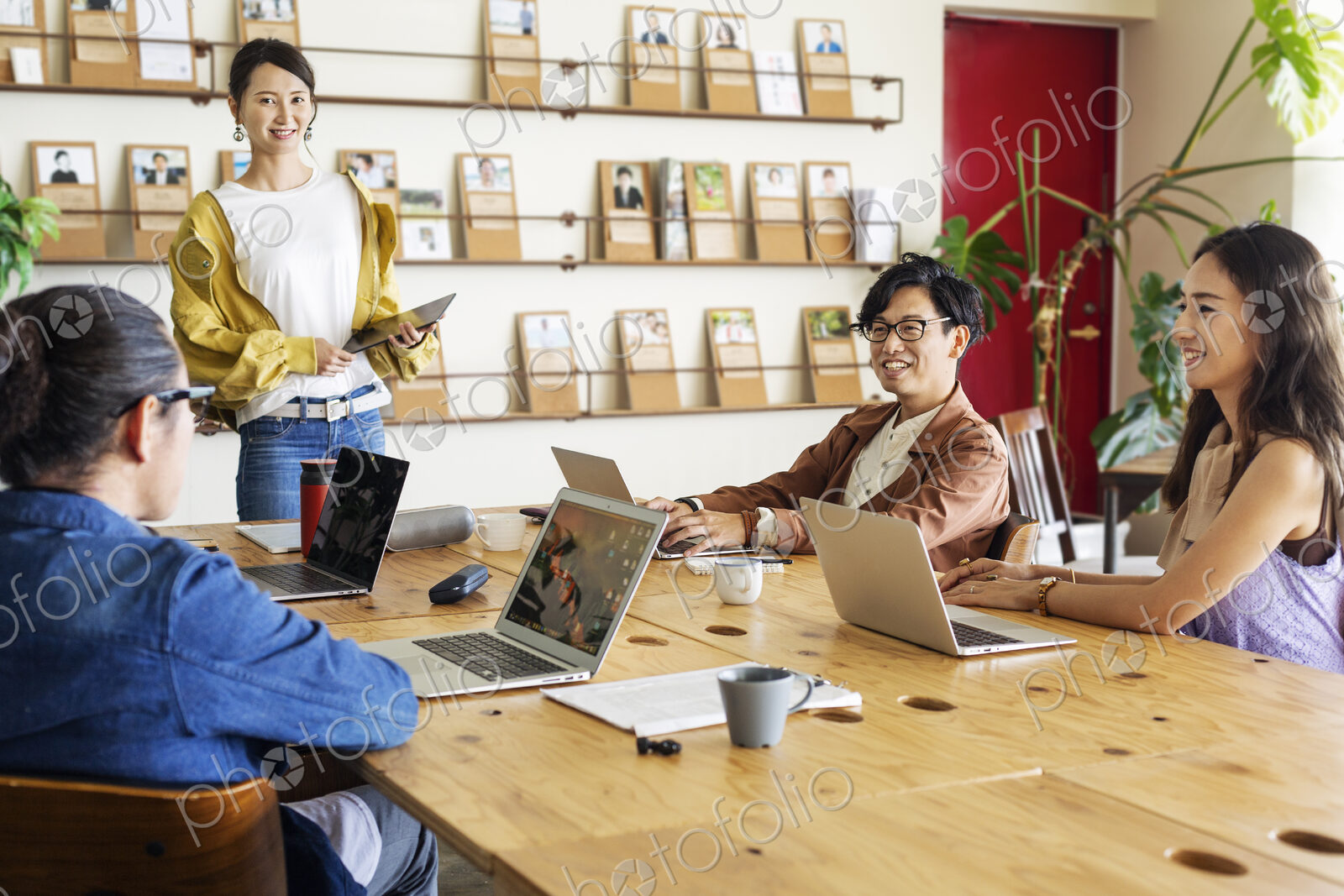 Group of young Japanese professionals working on laptop computers in a co-working space.