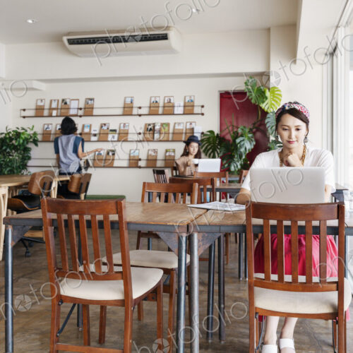 Group of young Japanese professionals working on laptop computers in a co-working space.