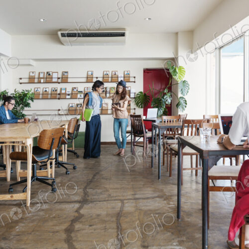 Group of young Japanese professionals working on laptop computers in a co-working space.
