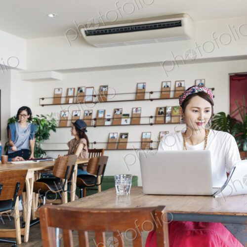 Group of young Japanese professionals working on laptop computers in a co-working space.