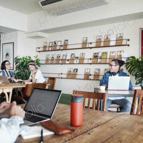 Group of young Japanese professionals working on laptop computers in a co-working space.