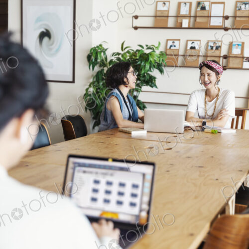 Group of young Japanese professionals working on laptop computers in a co-working space.