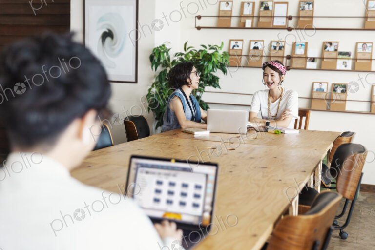 Group of young Japanese professionals working on laptop computers in a co-working space.