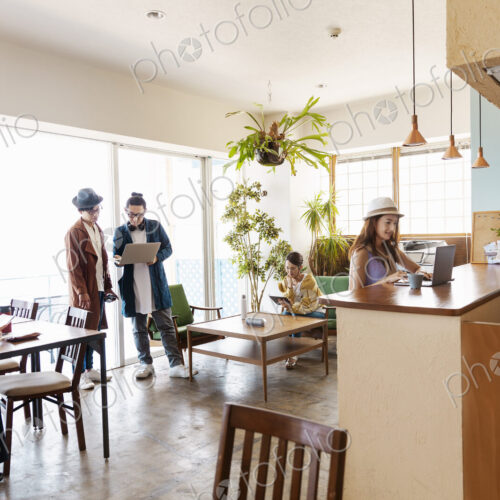 Group of young Japanese professionals working on laptop computers in a co-working space.