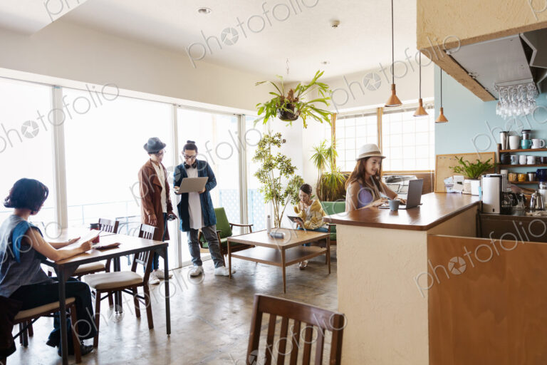 Group of young Japanese professionals working on laptop computers in a co-working space.