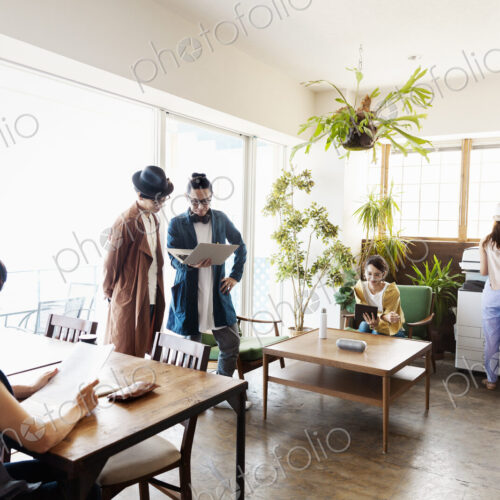 Group of young Japanese professionals working on laptop computers in a co-working space.
