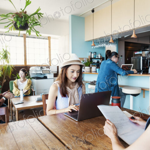 Group of young Japanese professionals working on laptop computers in a co-working space.