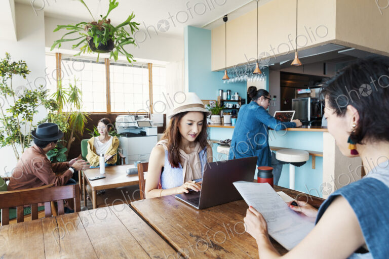 Group of young Japanese professionals working on laptop computers in a co-working space.