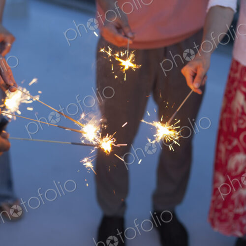 Group of young men and women with sparklers on a rooftop in an urban setting. Group of young men and women with sparklers on a rooftop in an urban setting.