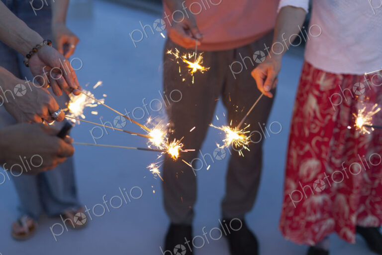 Group of young men and women with sparklers on a rooftop in an urban setting.