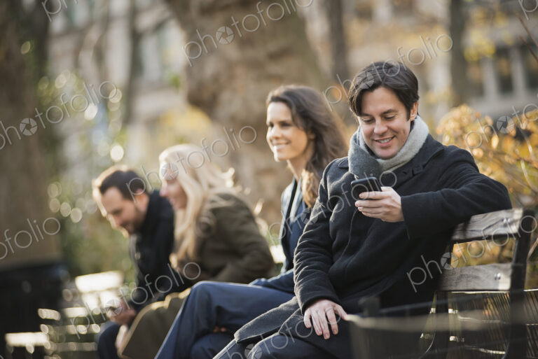 Group on bench in urban park using smartphones