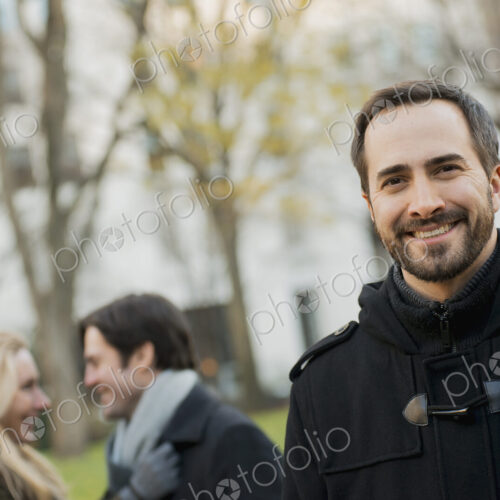Group walking in urban park, man in front Group walking in urban park, man in front
