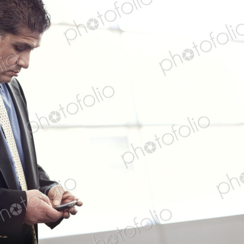 HIspanic businessman checking his cell phone in a conference centre lobby.